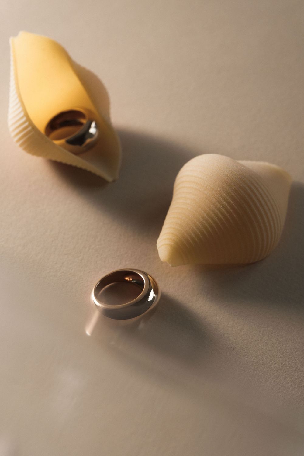 Close-up sequence of pasta shells in warm lighting casting soft shadows on a neutral surface.