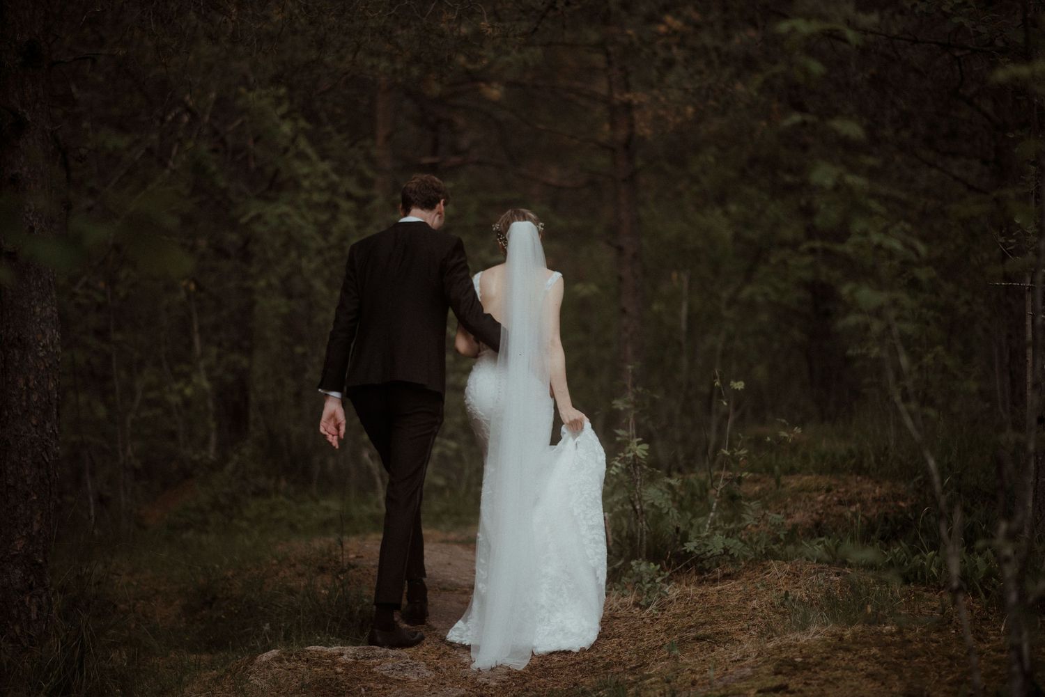 A romantic silhouette of a couple by a sparkling lake in wedding attire in Oslo at Holmenkollen.