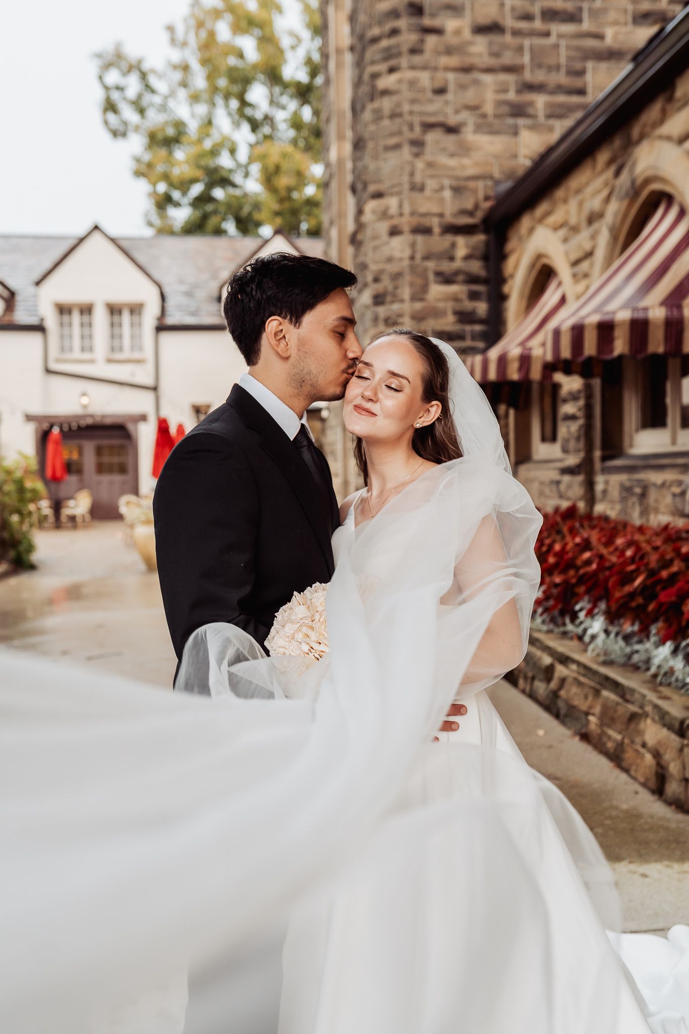 A couple shares a tender moment during their outdoor wedding ceremony with rolling hills and green trees in the background.