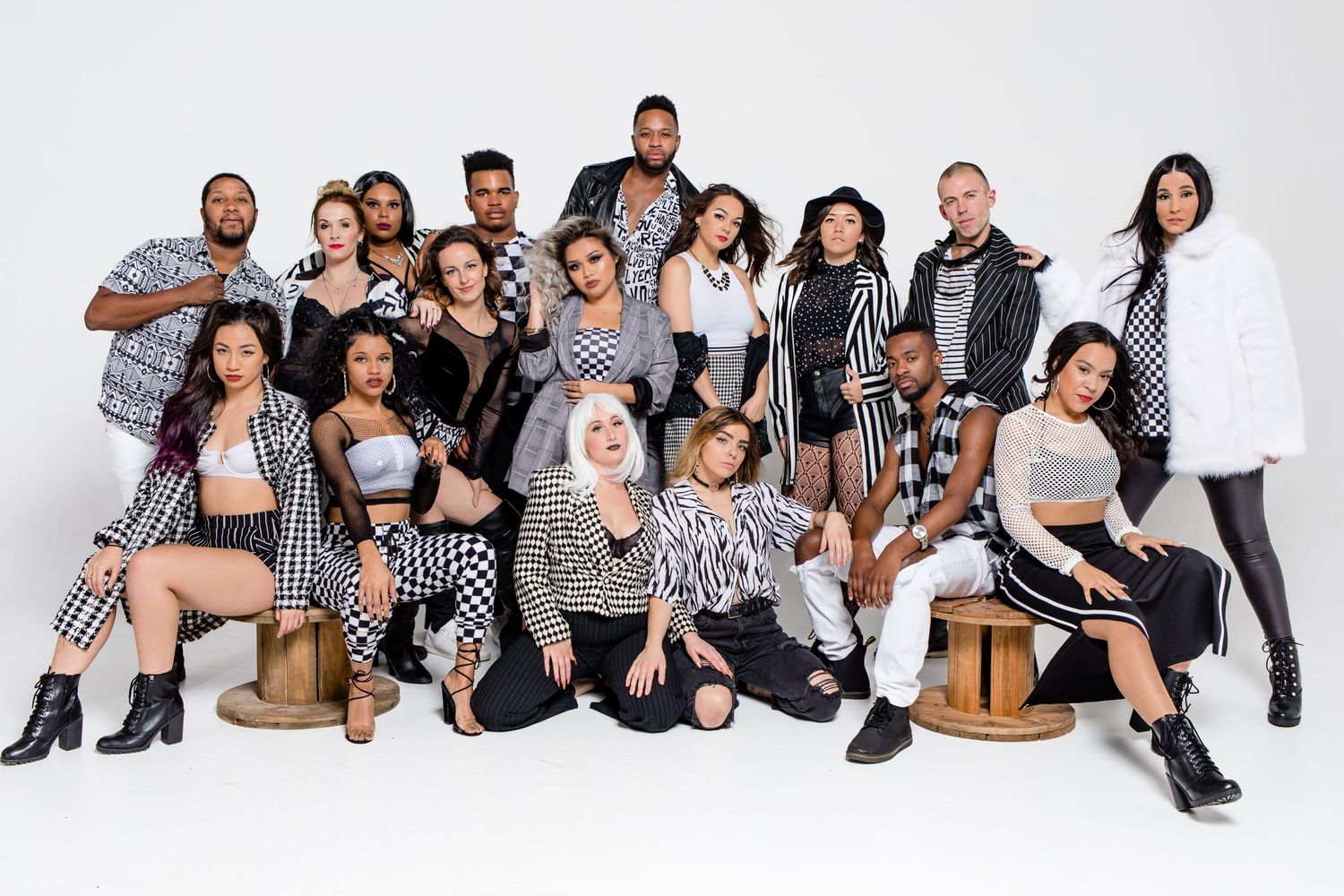 Diverse group in black and white coordinated outfits posing together against a white studio background.