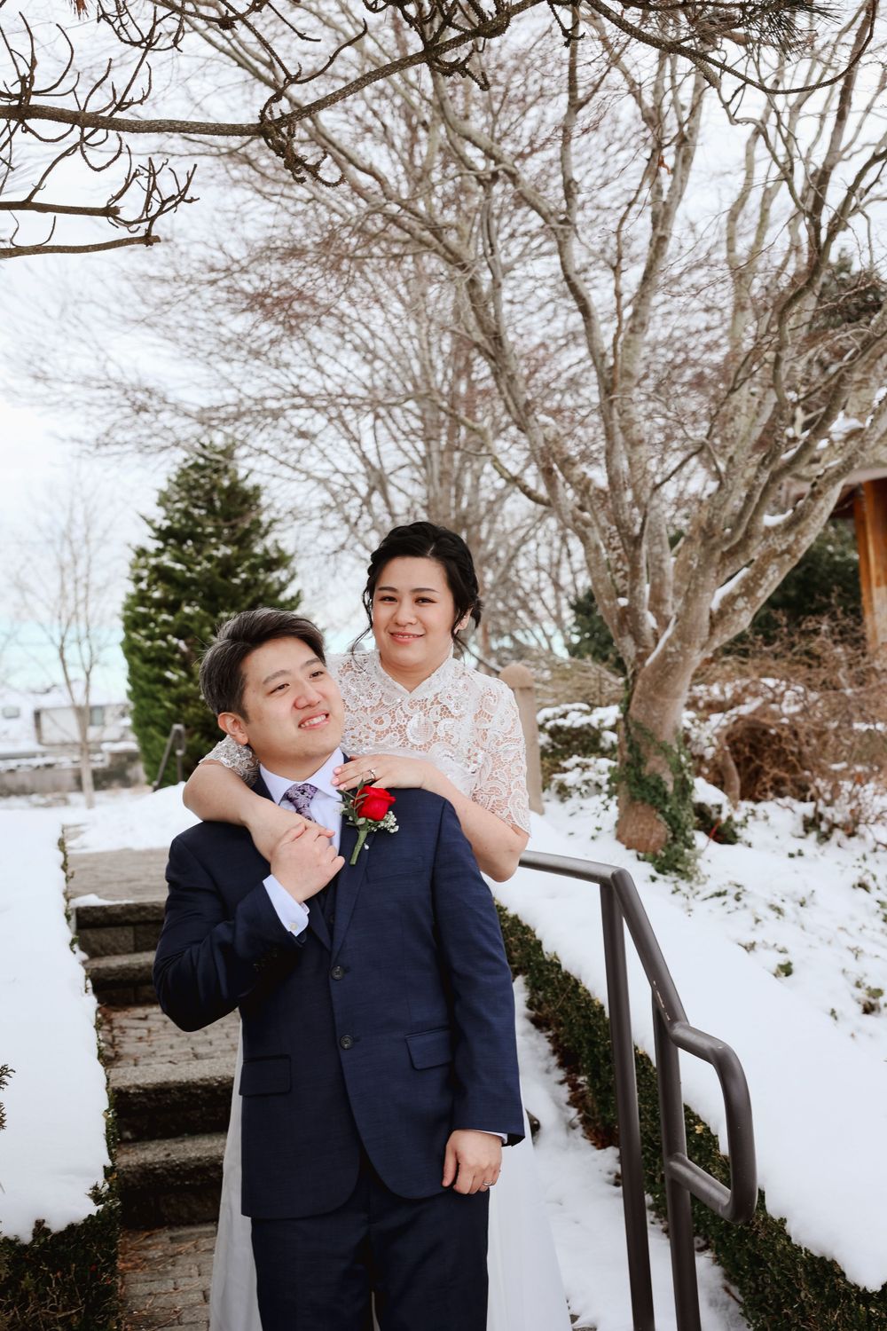 A couple shares a playful moment on snowy outdoor steps during their winter wedding photoshoot. smilein wedding photography vancouver