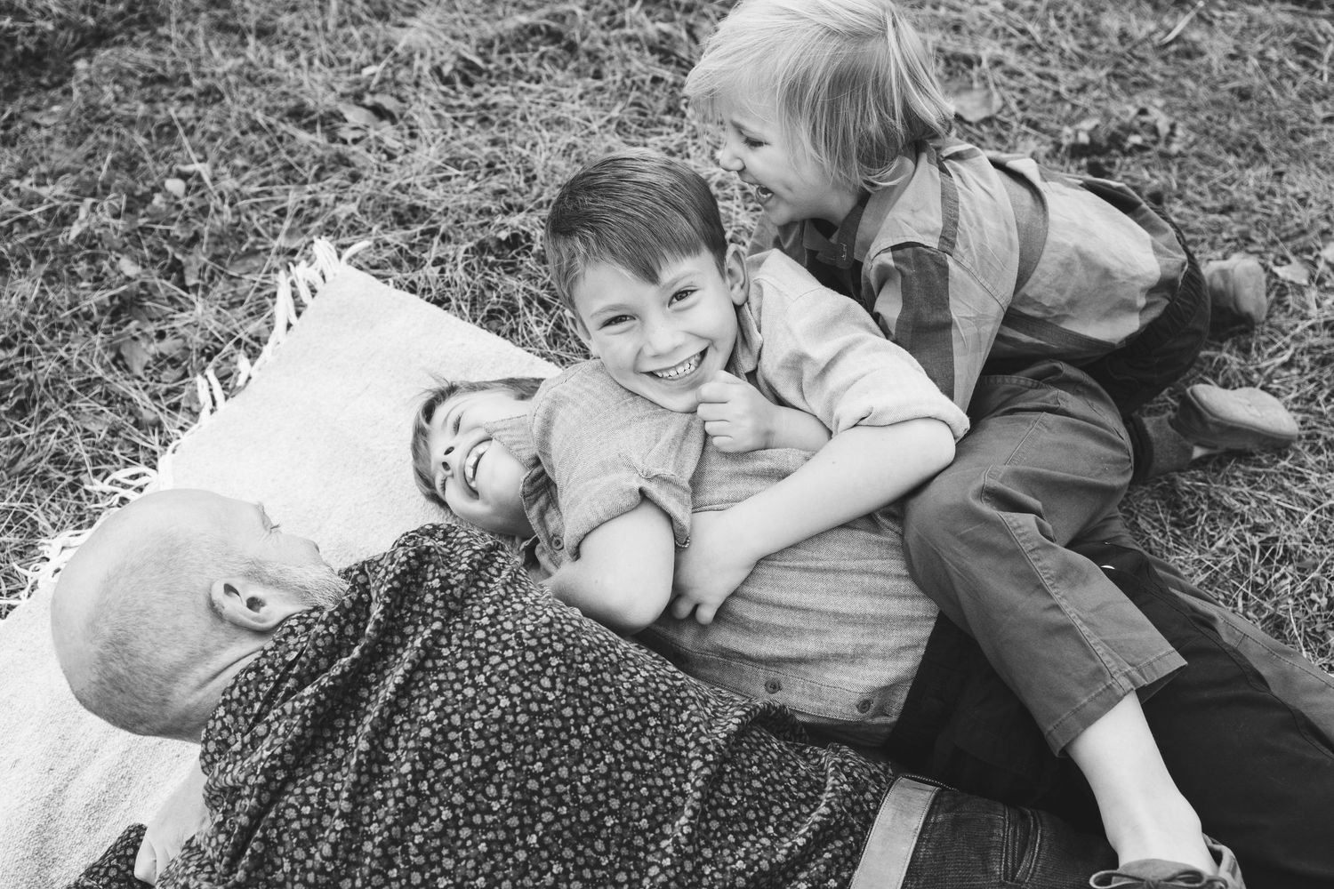 A family sitting together on a blanket enjoying a sunny day in the mountains.