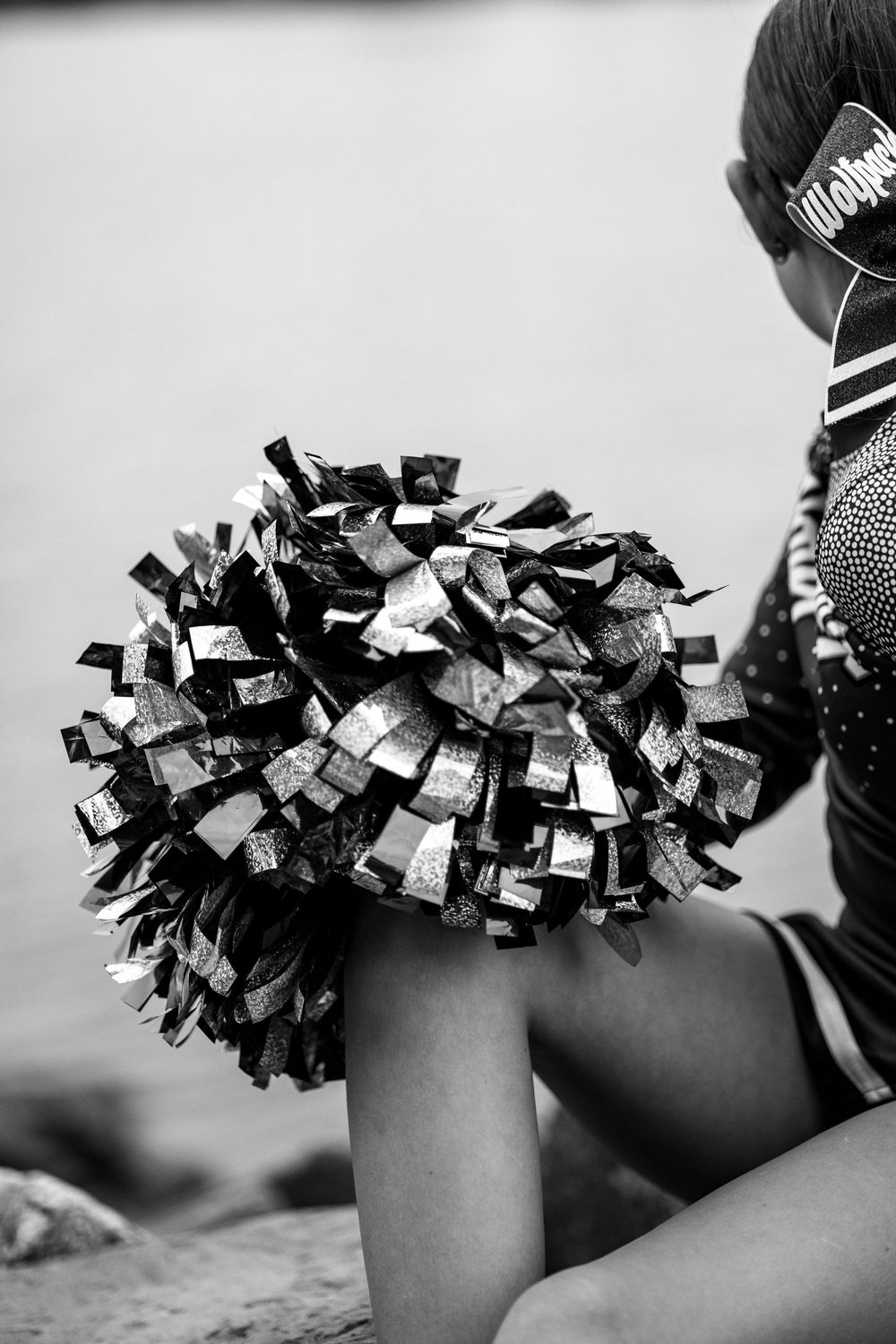 Black and white photo of a cheerleader's metallic pom pom held up against a plain background.