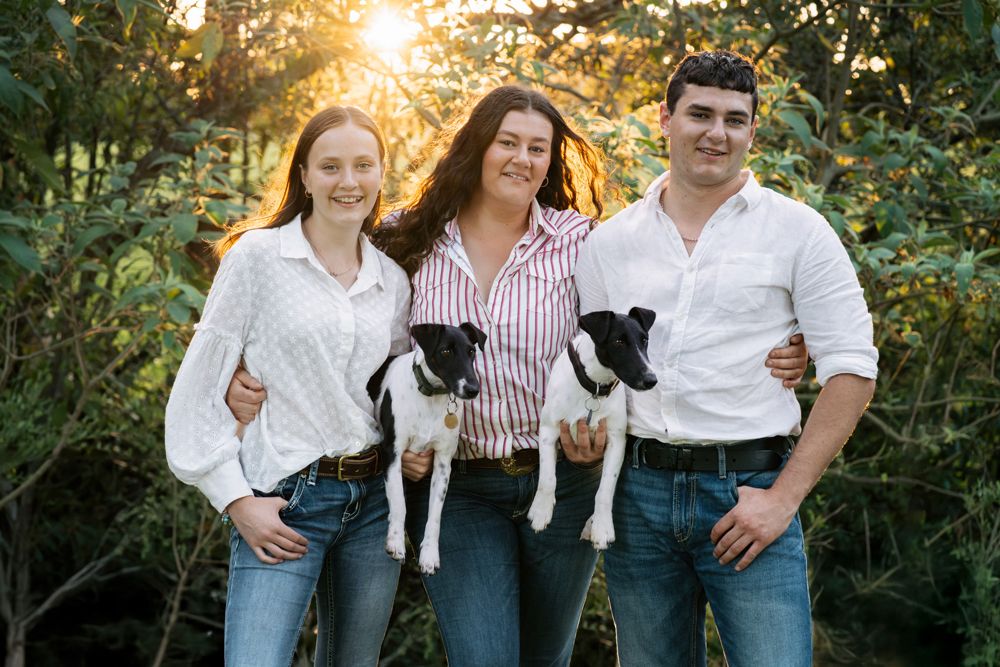 Siblings with their two fox terriers in the orange sunset light photographed during a dog friendly family photoshoot in the central cost