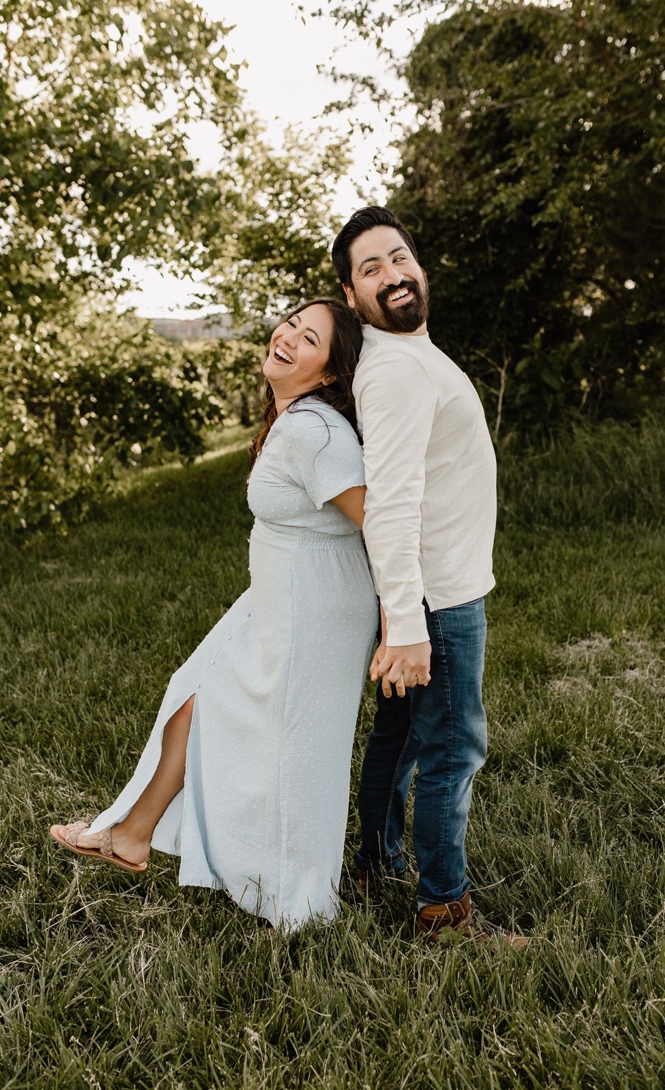 Couple shares joyful laughing moments together in a grassy outdoor setting.