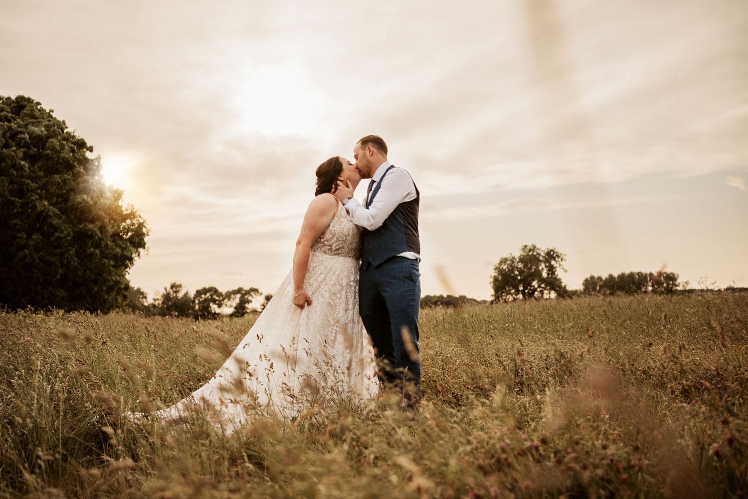 Newly wed couple kissing having their best day as the sunsets behind them