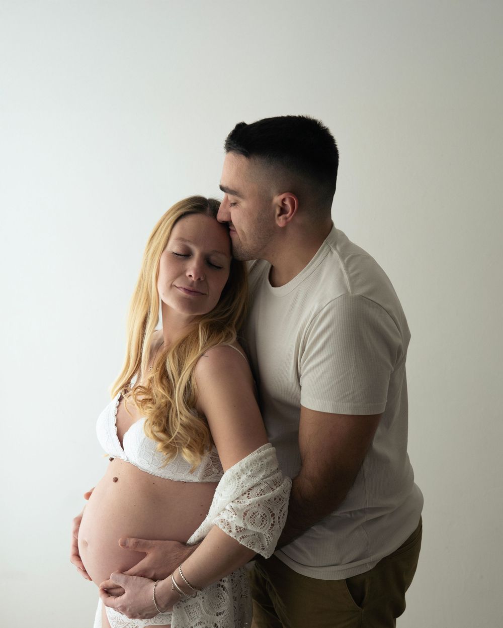 Coppia di futuri genitori si abbraccia durante un servizio fotografico
