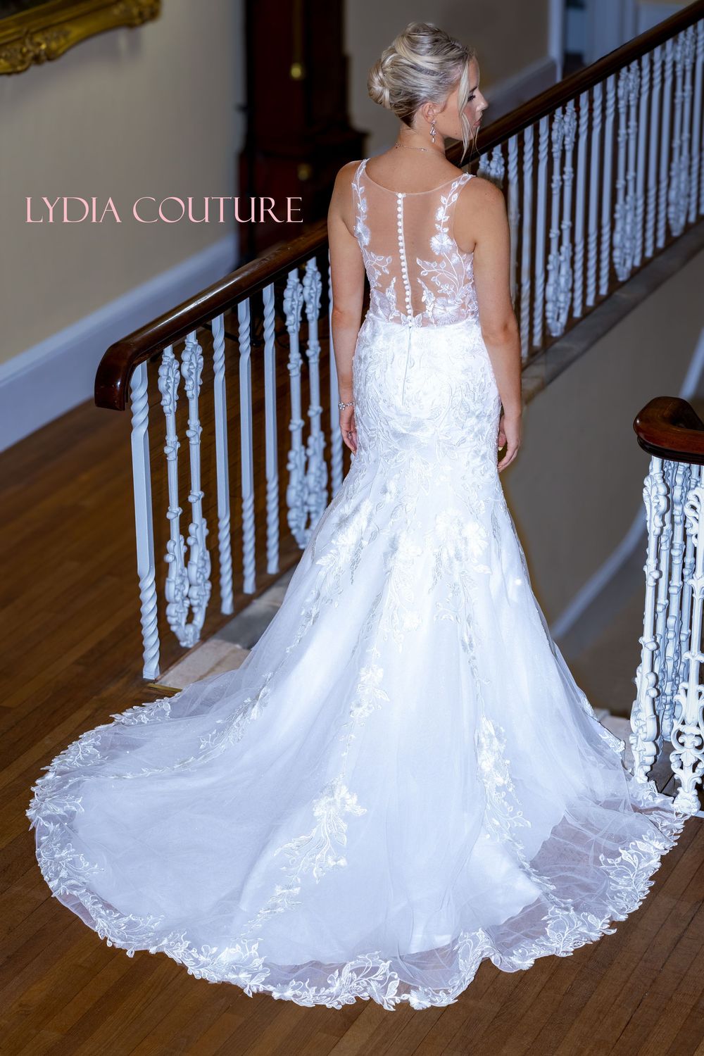 Back view of a mermaid style wedding gown with sheer illusion back, lace appliques and dramatic chapel train by Lydia Couture.