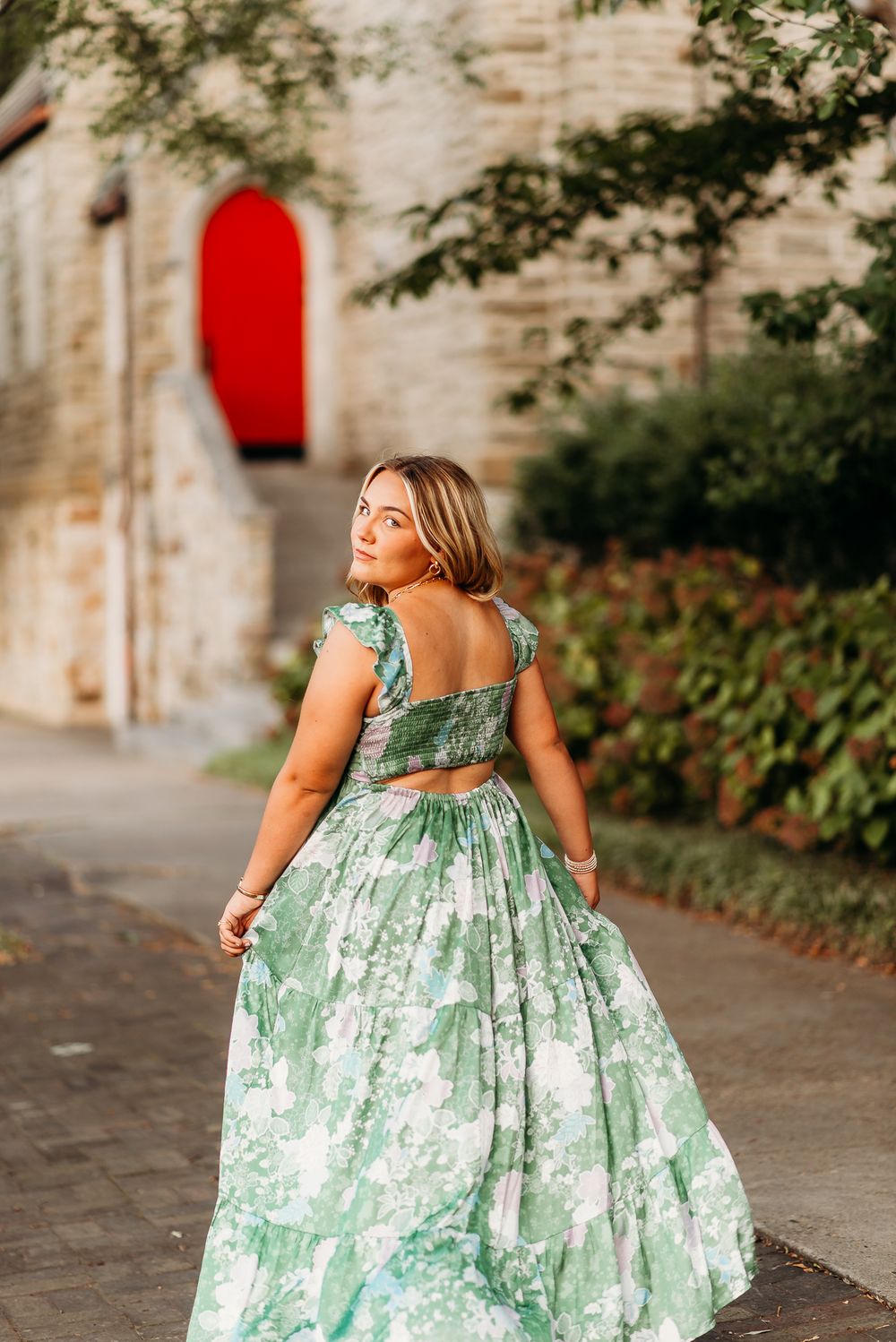 Back view of floral green dress against stone wall with red door accent.