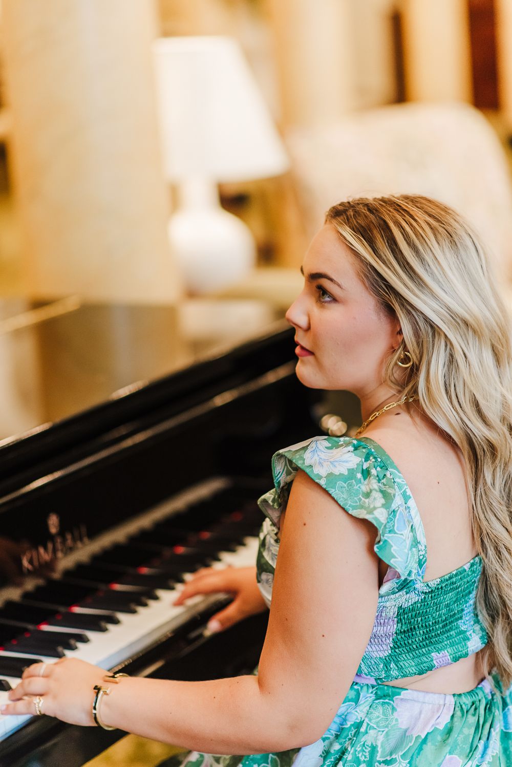 Side profile view of person in green dress playing piano indoors.