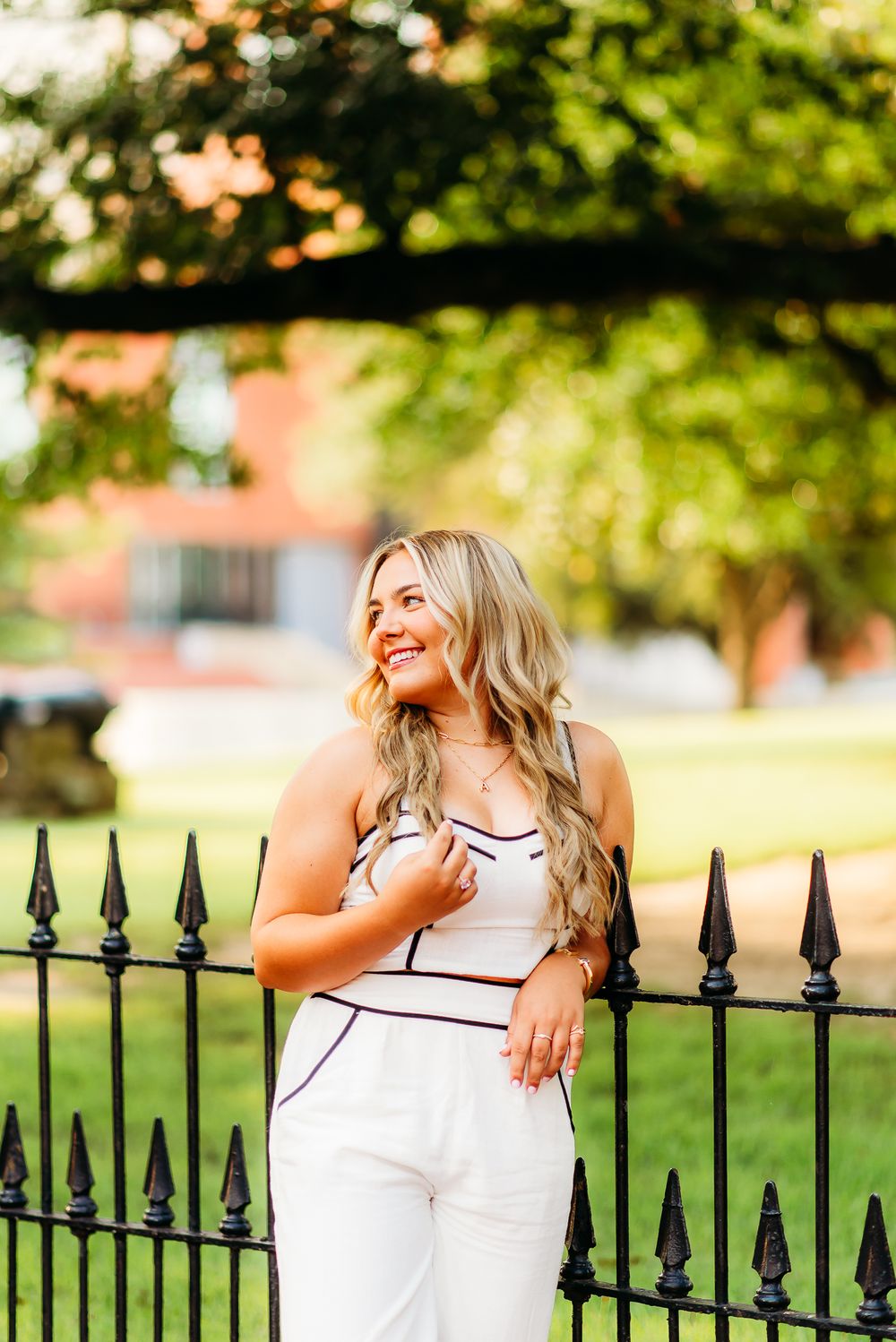 Outdoor lifestyle portrait against ornate black iron fence with garden background.
