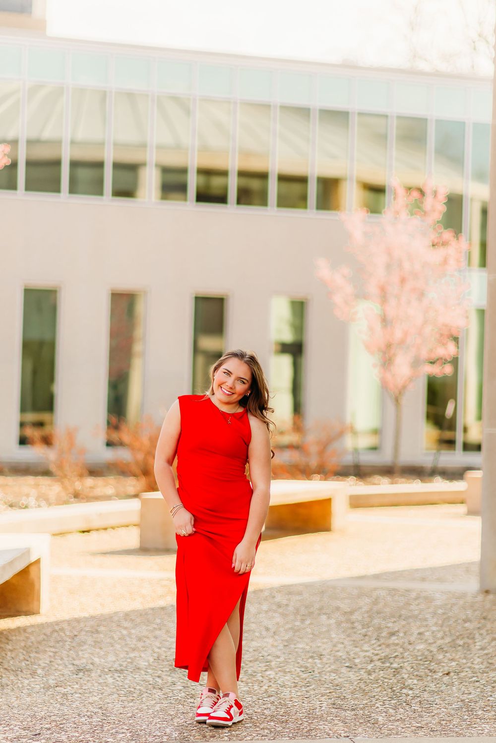 Stylish red maxi dress look with sneakers in urban courtyard setting.