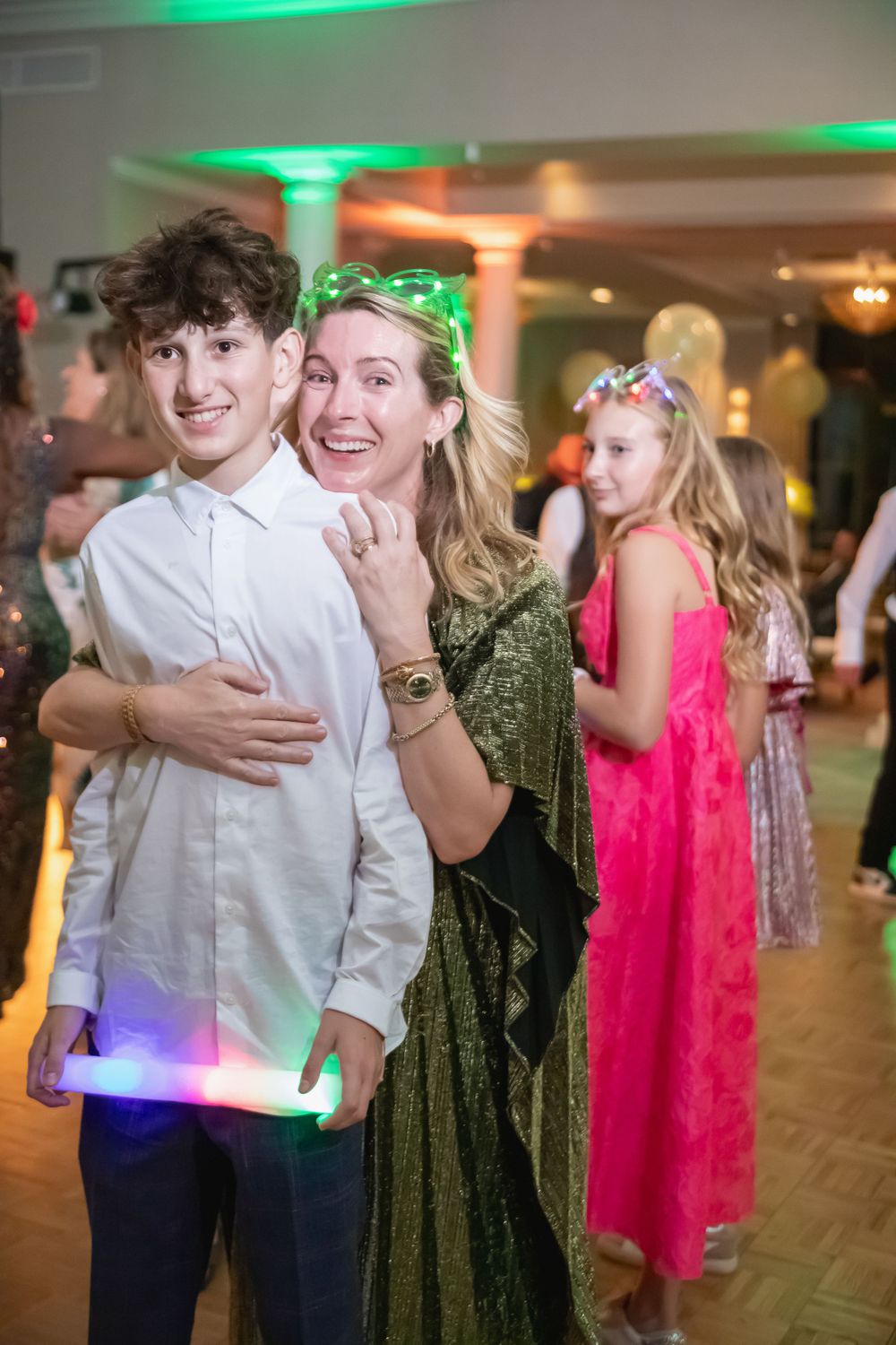 Guests enjoying a lively dance party with colorful lighting and festive atmosphere at an indoor venue.