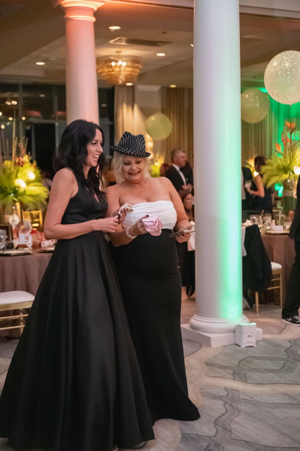 Wedding guests dance and celebrate on a dance floor with illuminated columns and elegant decor.