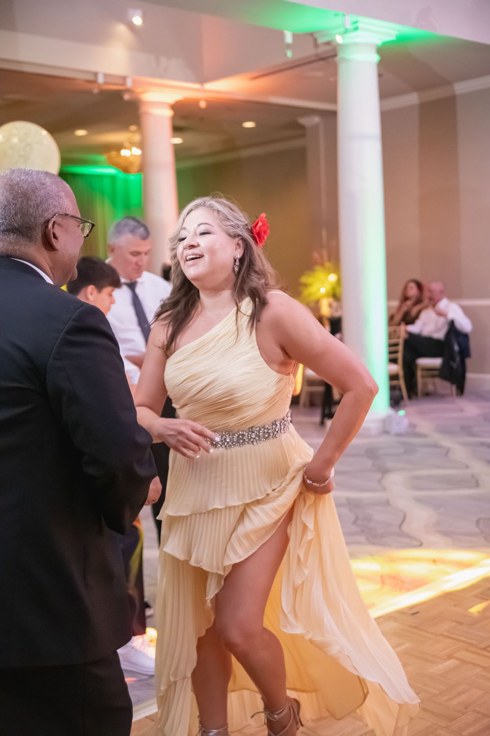 Dancers in formal attire twirl and move across a polished dance floor at an elegant reception.