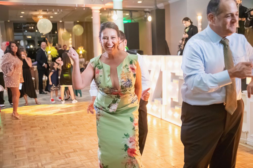 Couples dancing together at an elegant indoor reception with decorative lighting and columns.