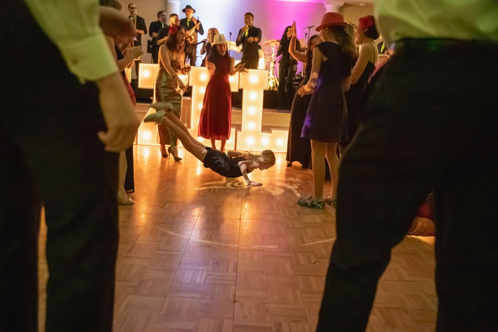 Low angle view of dancers' feet moving on a polished wooden dance floor at an event.