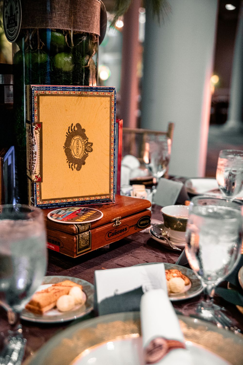 Ornate cigar boxes displayed on a formal dining table with place settings.