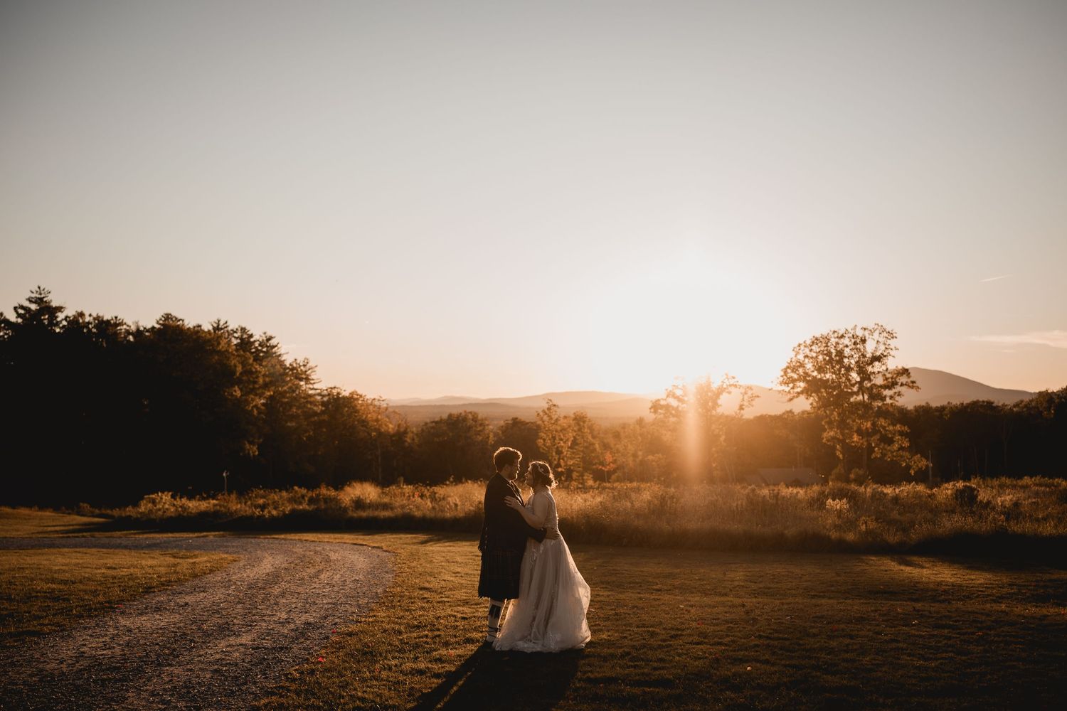 A dramatic sunset silhouette shot of a wedding couple in a rural landscape.
