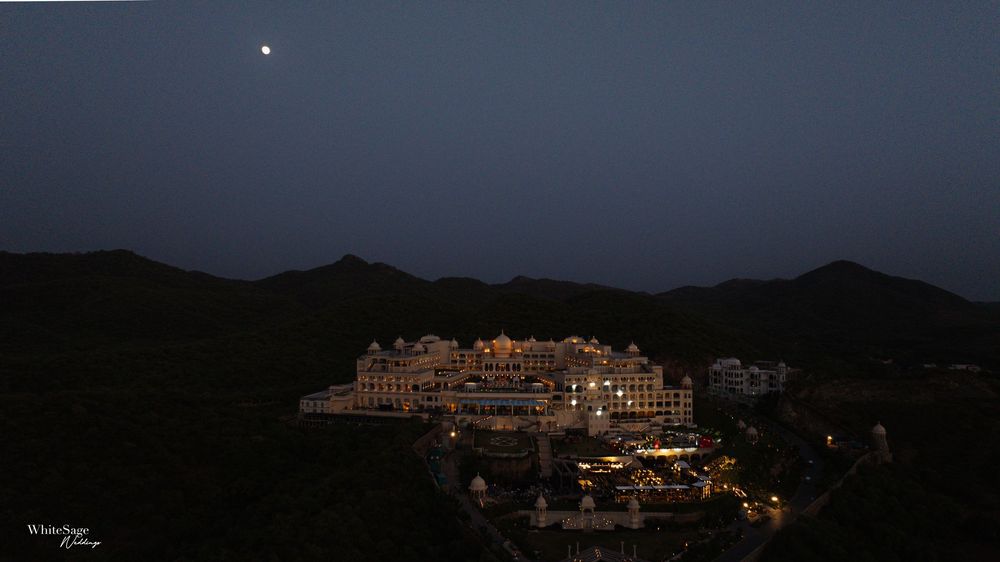 Illuminated palace-like hotel complex nestled in dark mountains under a starlit night sky.