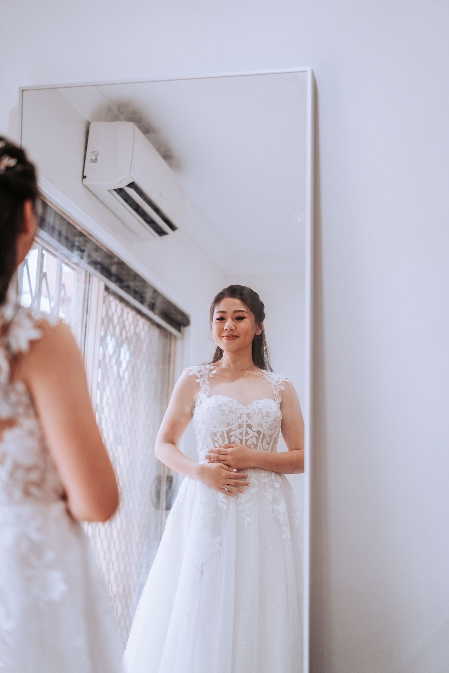 A reflection in a mirror shows someone wearing an elegant white lace wedding gown.