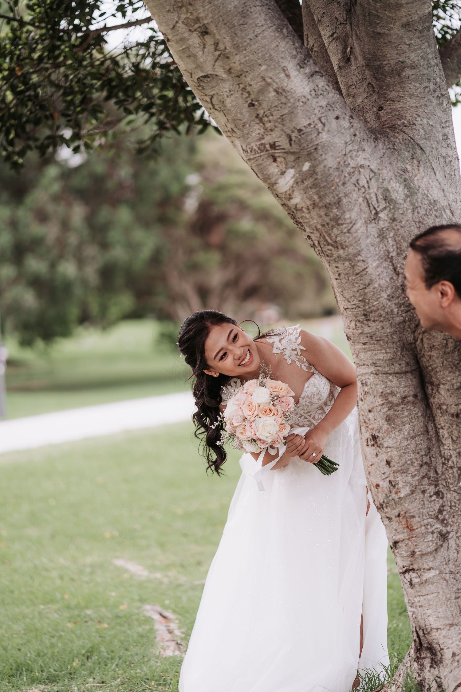 A joyful wedding moment captured under a large tree in a garden setting.