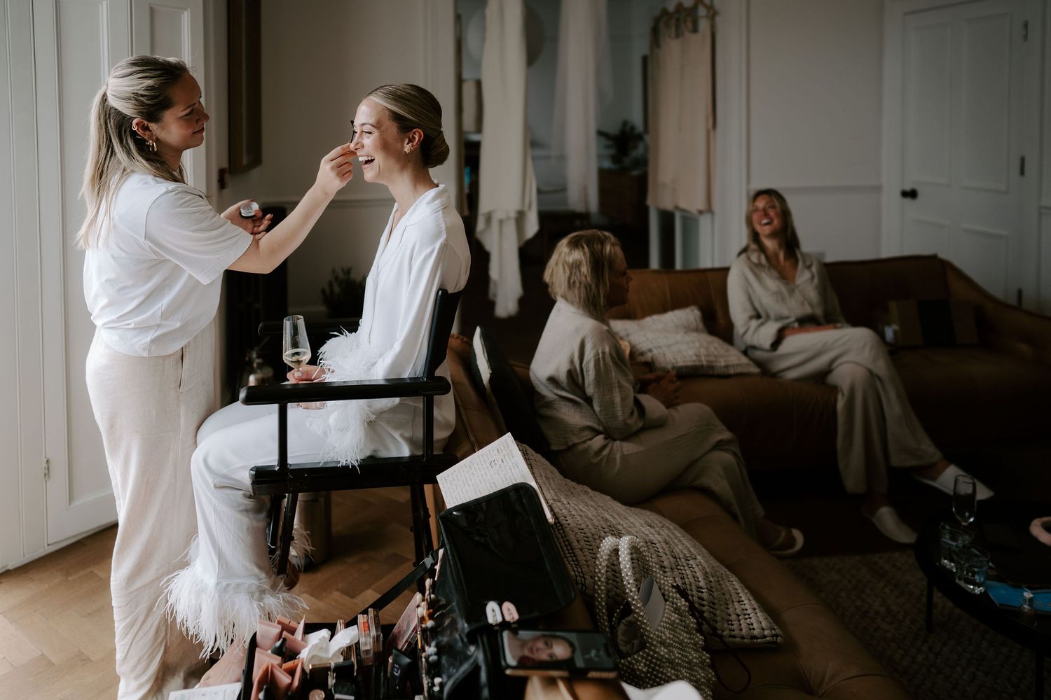 Tunnels Beach Wedding Venue in North Devon, Bride sat in chair getting make up done with bridesmaids