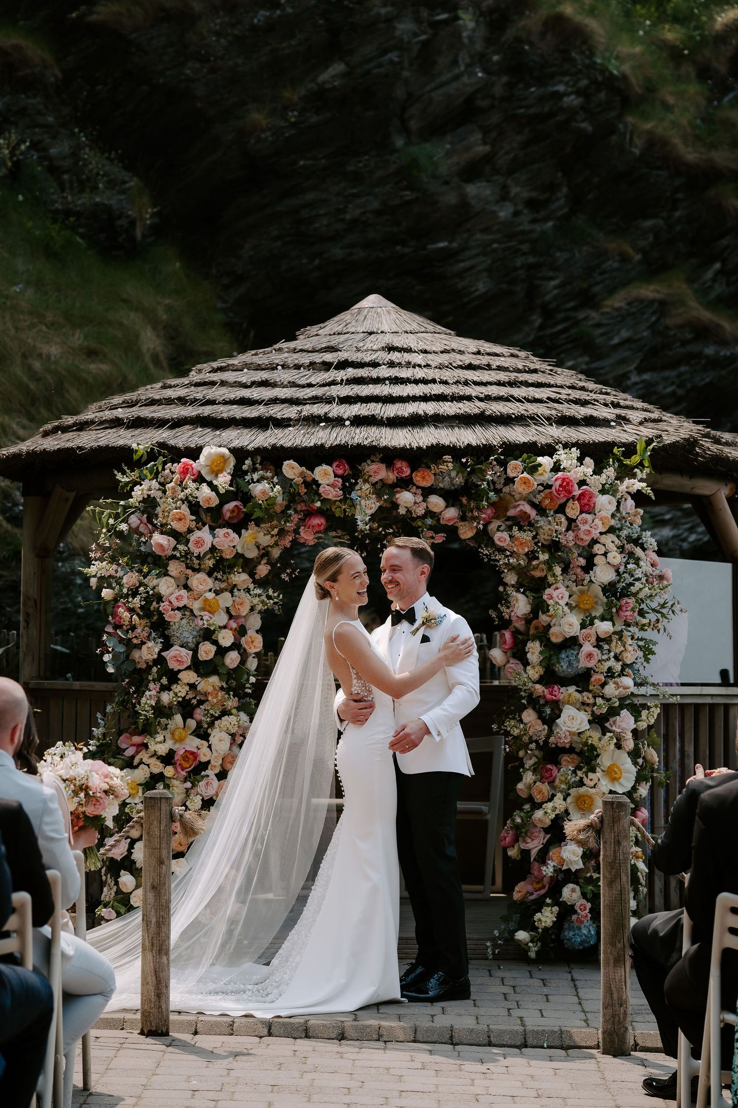 Bride and Groom in front of floral arch next to the sea at Tunnels Beach Wedding Venue in North Devon