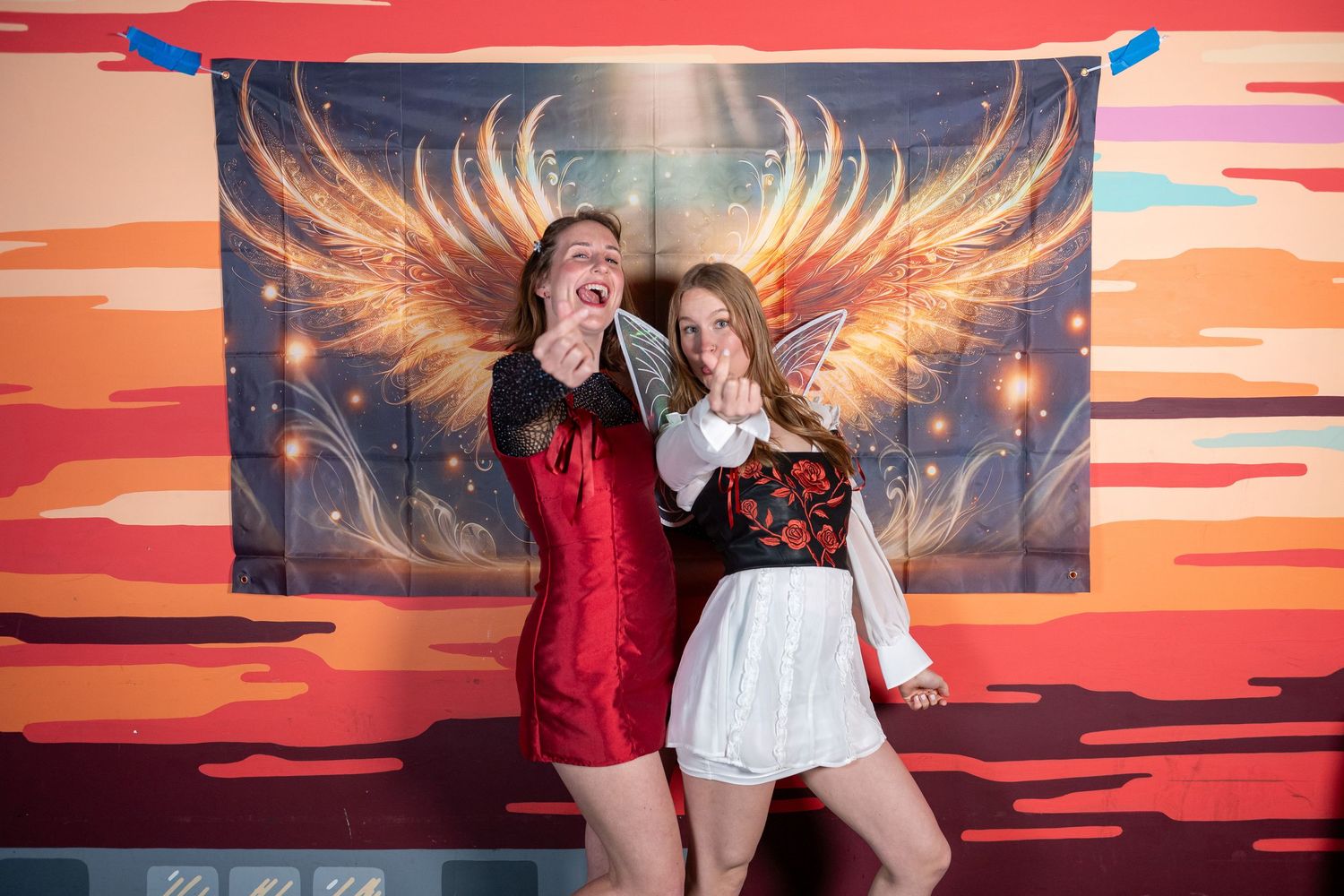 Festive group poses together by illuminated angel wing wall art with sunset colors.
