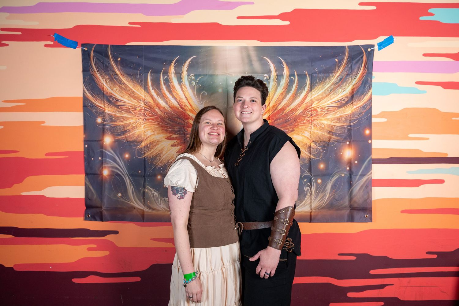 Group photo against a colorful wall mural featuring fiery wings and sunset colors.
