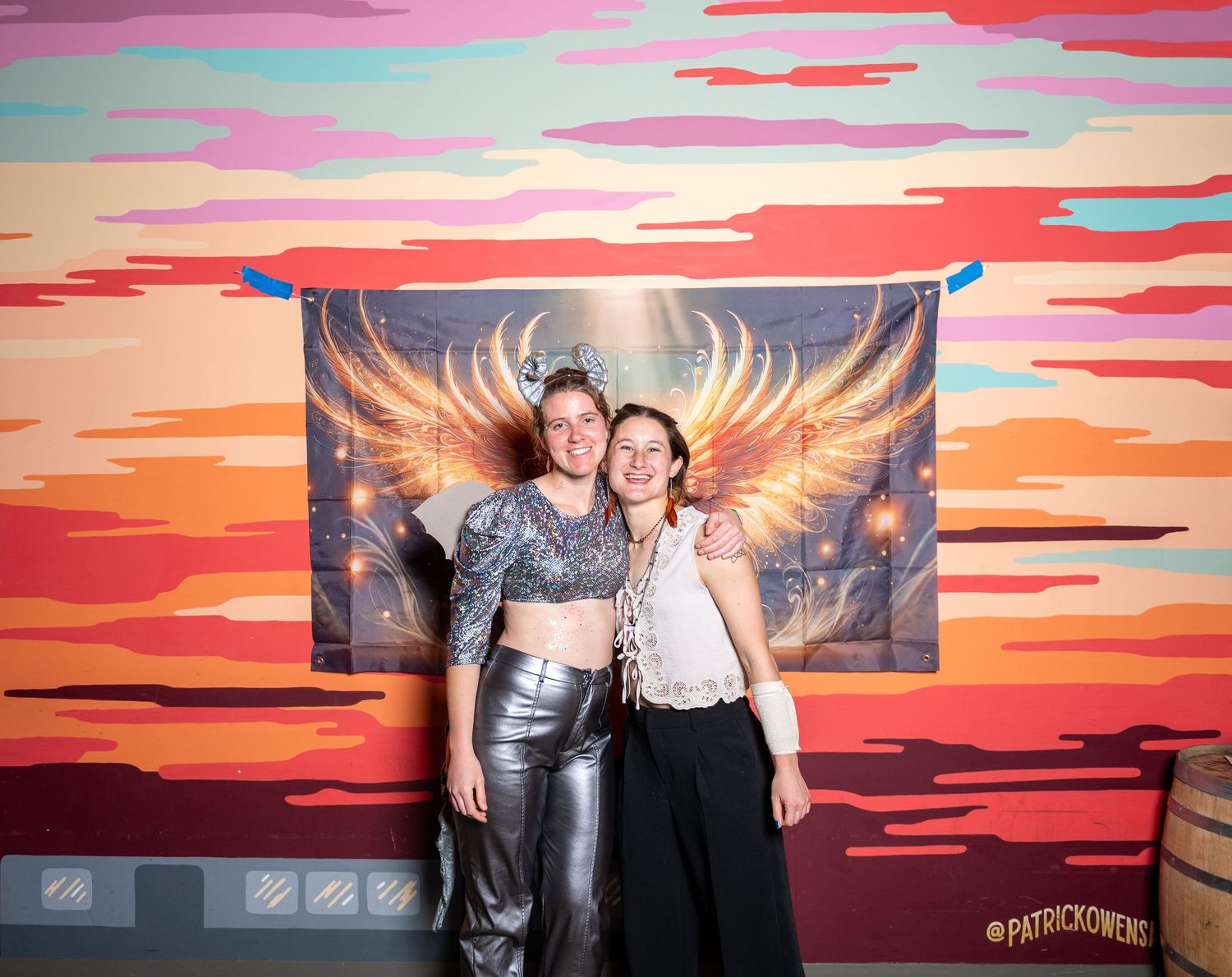Group photo session against a colorful sunset mural with golden wings design.