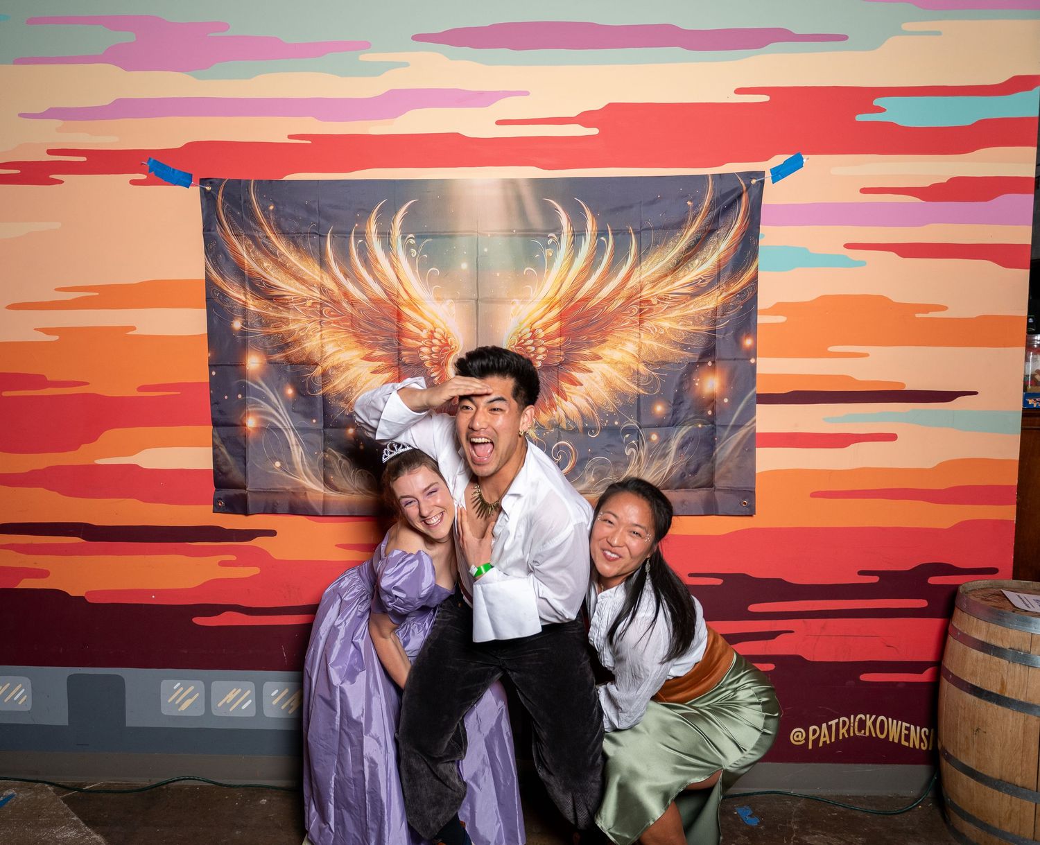 A series of photo booth style images showing people posing against a vibrant sunset backdrop with glowing wings.