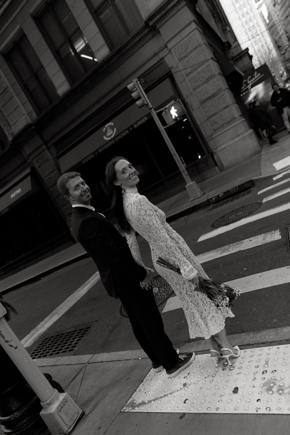 A black and white sequence of photos showing two people crossing a city street in formal attire.