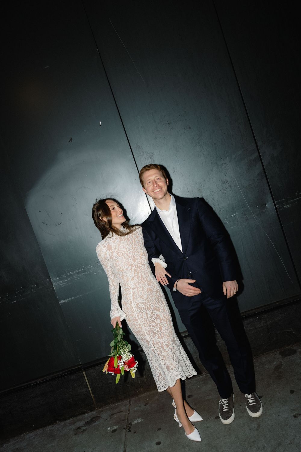 A couple poses together against a dark wall in a series of candid nighttime photos.
