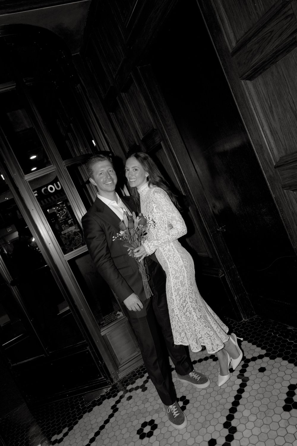 A black and white photo sequence shows a couple dancing and spinning on a hexagonal tiled floor in a dark room.