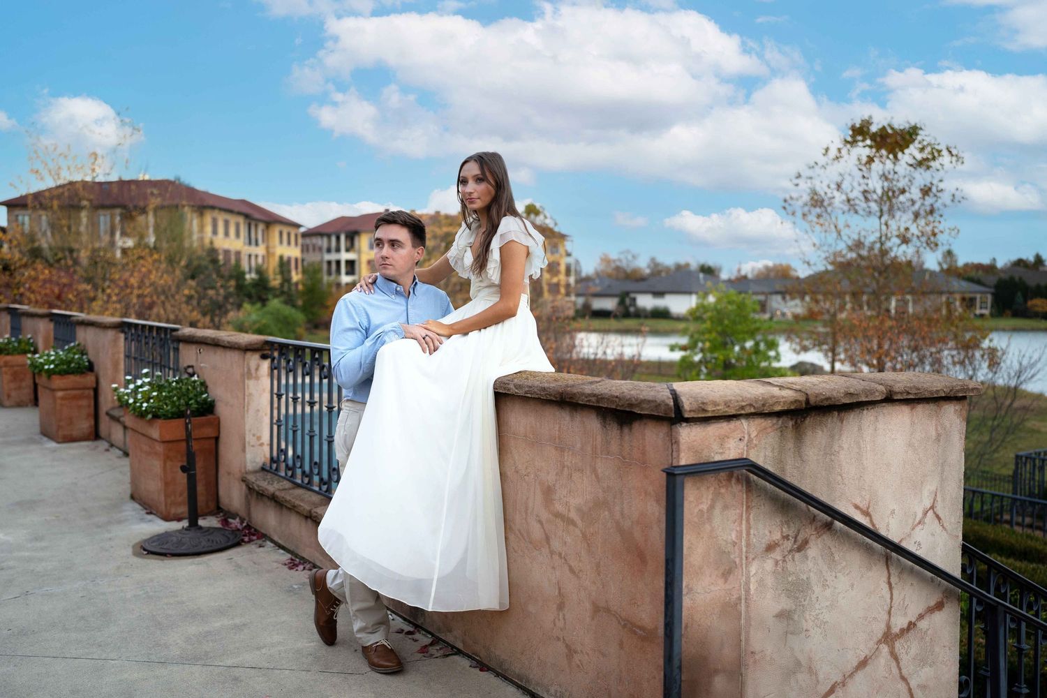 A couple in wedding attire poses on a stone wall overlooking a scenic landscape on their special day.