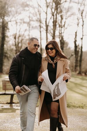 Couple walking and laughing together in a sunny park setting during autumn.