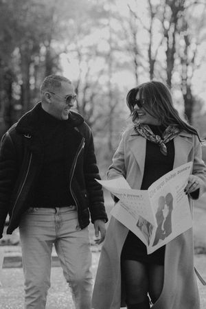 Playful couple looking at papers while walking outdoors in a park.
