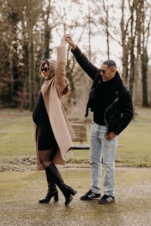 Two people dancing and having fun together in a park setting.