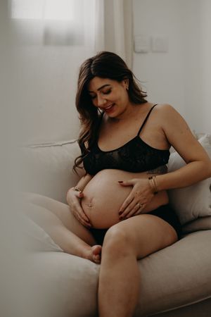 Intimate maternity portrait on couch showing pregnancy belly in natural light.
