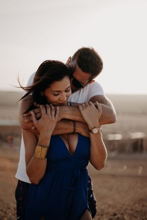 Romantic couple embracing in desert landscape during golden hour.