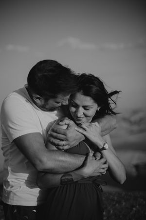 Black and white portrait of couple sharing intimate embrace outdoors.