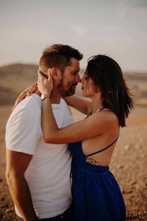 Romantic couple in casual wear sharing intimate moment against desert backdrop.
