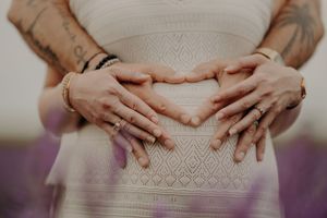 Close-up shot of hands resting on a white lace dress.