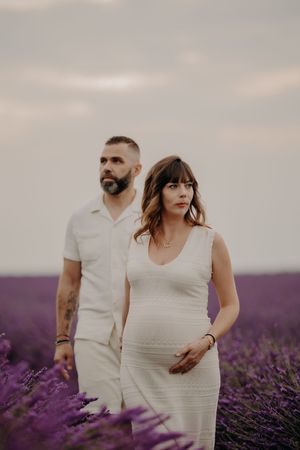 A couple stands together in a vast field of blooming purple lavender.