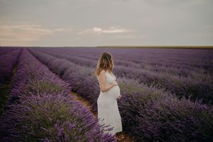 Romantic couple poses together in a vast field of purple lavender flowers.