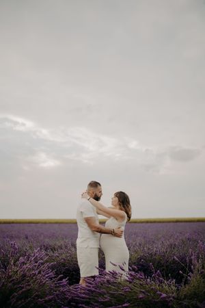Couple dancing and embracing in a blooming purple lavender field under cloudy skies.