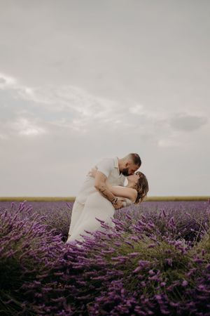 Two people share an intimate moment while surrounded by rows of flowering lavender.