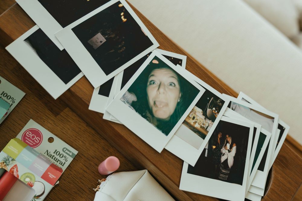 A collection of instant polaroid photographs scattered on a wooden surface showing various memories and moments.