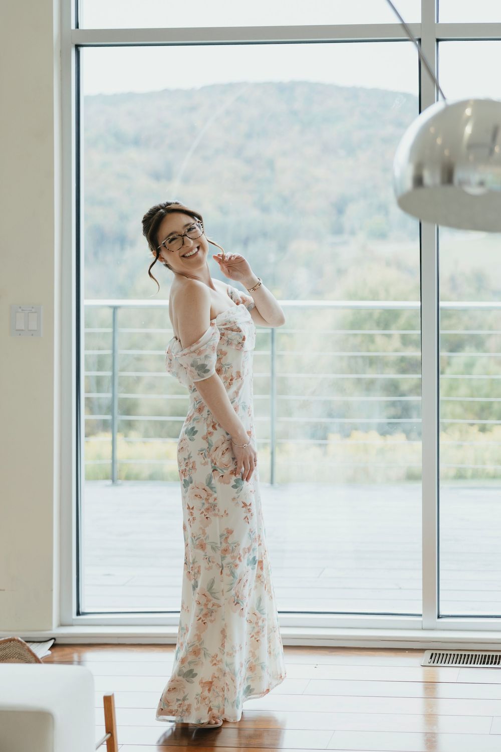 Elegant floral dress photographed in a bright room with large windows overlooking mountains.